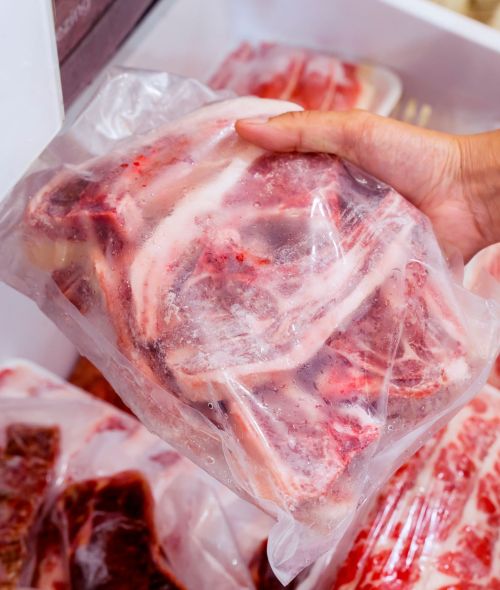 Hand choosing fresh raw ribs meat in freezer Closeup of hand choosing fresh raw ribs meat in the freezer